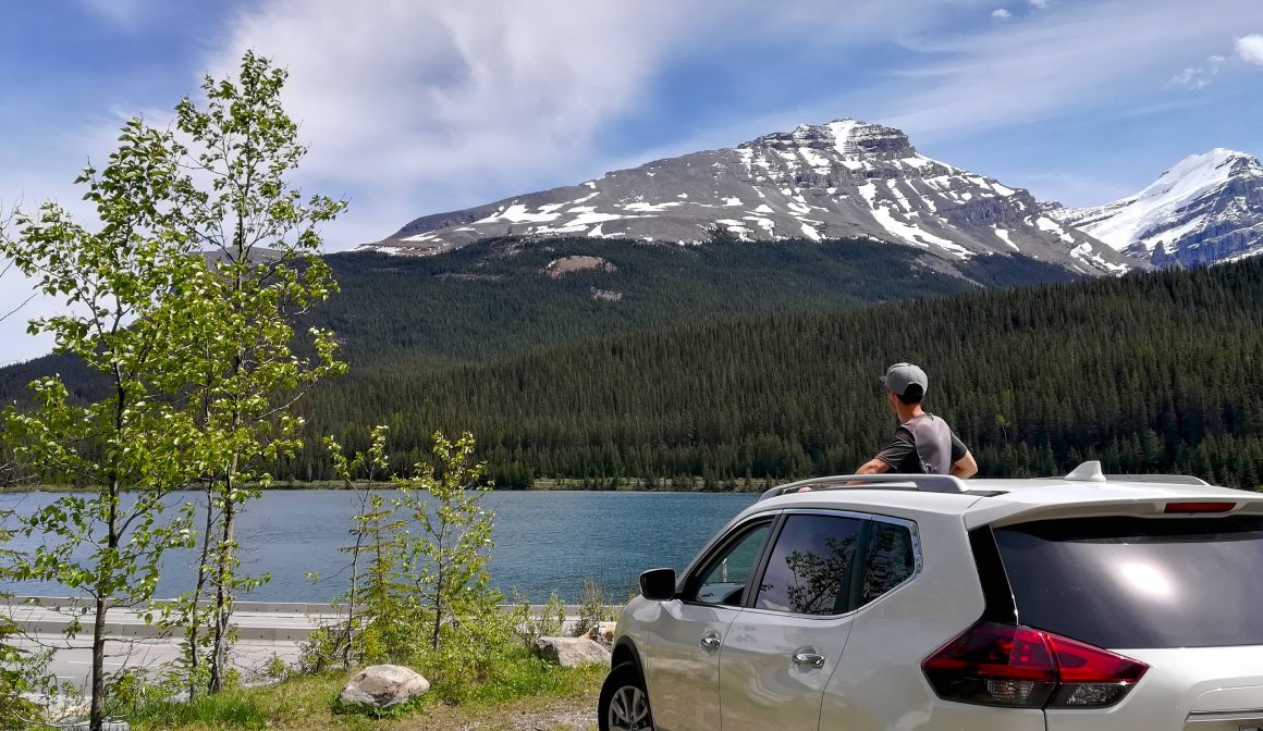 Persona que sale del coche en un parking en Canadá con vistas a un lago